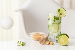 Sindirimi Rahatlatan Tarifler: Bayram Sonrası İçin Sağlıklı ve Lezzetli Öneriler Mojito cocktail with lots of ice, white rum, lemon juice and tonic, decorated with lime slices and mint leaves on a modern white table