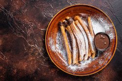 churros youtiao sıcak çikolata tulumba tatlısı Spanish tapas churros with sugar and chocolate sauce. Dark backg