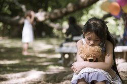 Babasız çocuk olmanın etkileri, mitler ve gerçekler; baba, anne ve toplum açısından sorumluluk çerçevesi. babasız çocuk ve tek ebeveynli aile psikolojisi Sad girl hugging teddy bear sitting under tree sadness in green park. Lonely girl feeling sad